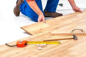 homme soulevant du parquet laminé-min